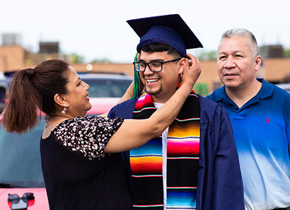 Mother fixing son's graduation cap as father looks on