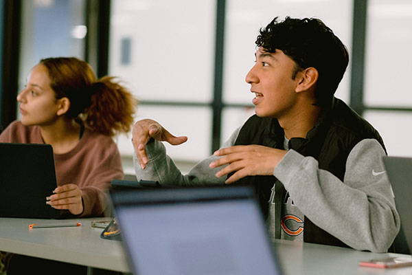 Seated female and male students talking in class