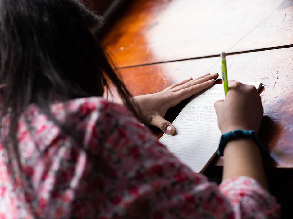 Female student composing story with pen on pad of paper
