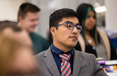 Male student in suit and tie, listening intently