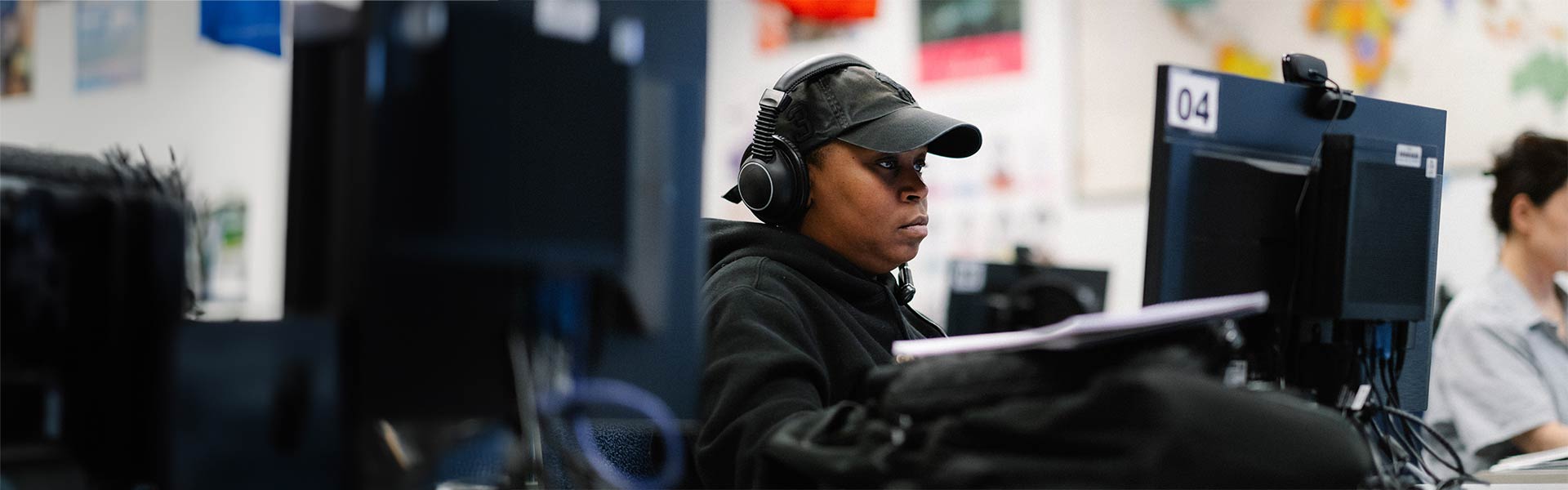 Student sits at computer with headphones working