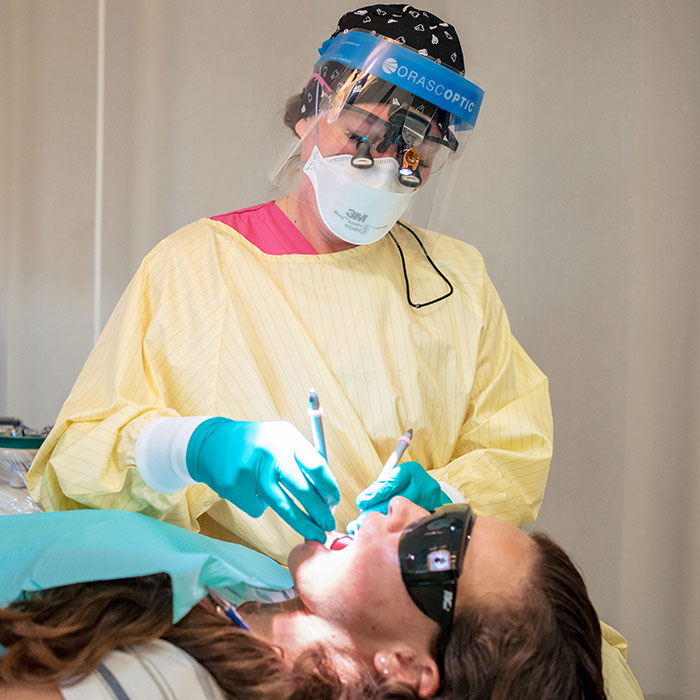 A dental hygiene student provides care to a patient.