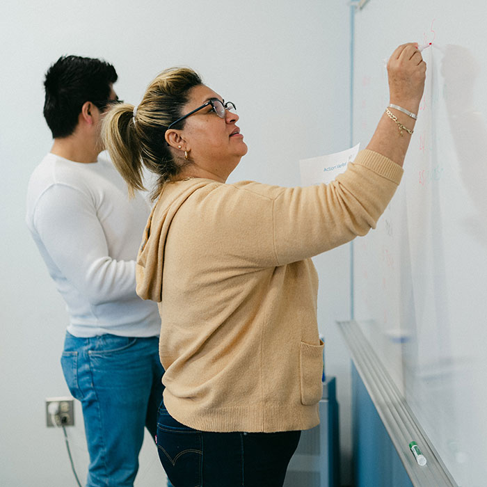 Two ESL students write words on the whiteboard in the classroom.