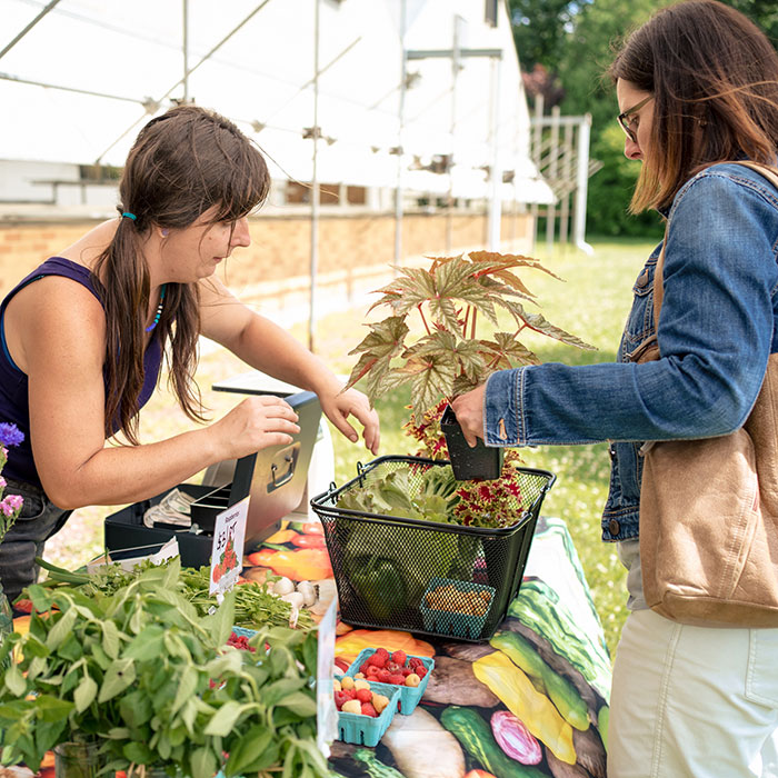 Woman buying flowers and veggies at the Farm Market