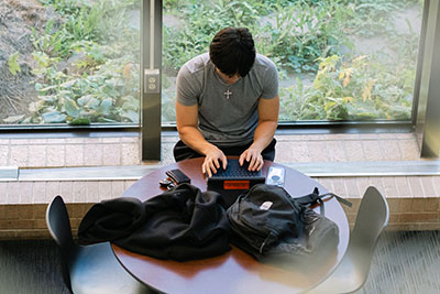 Student working on laptop near window