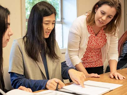 Mentor works with student reviewing a notebook