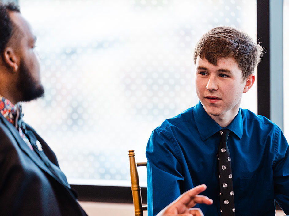 Two men are sitting down in professional clothing discussing