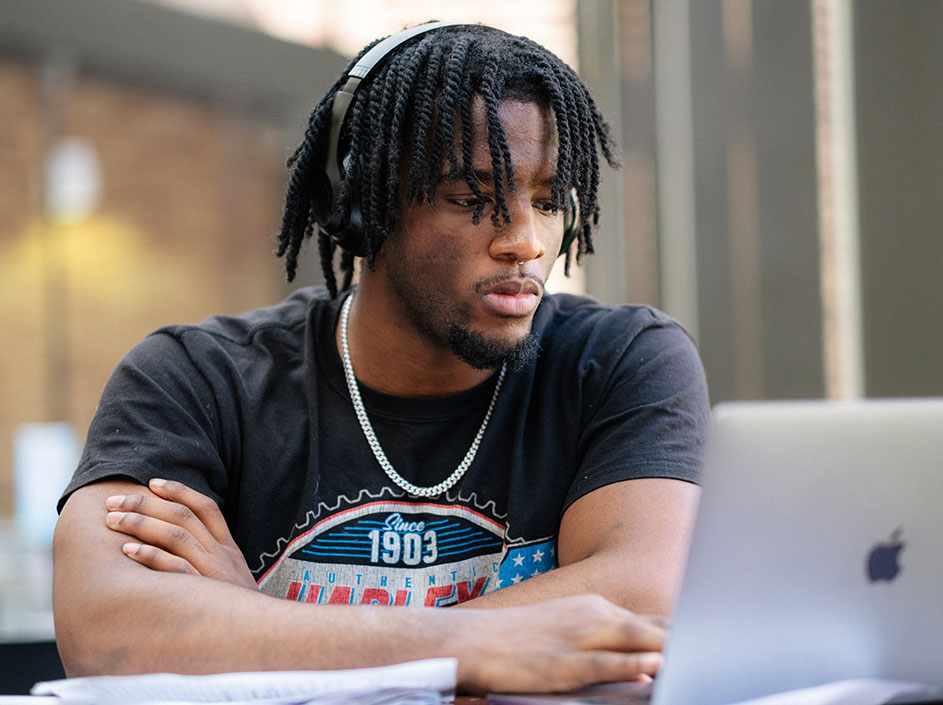 Male student wearing headphones, looking at computer