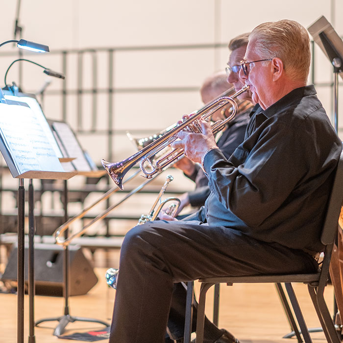 Community musicians in the horn section perform a musical number