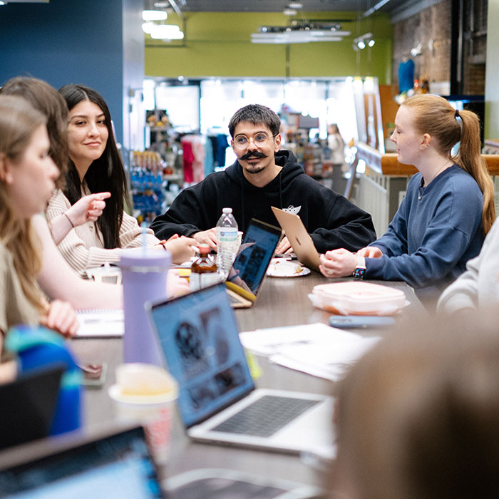 Students meeting around a table to work on a class project.