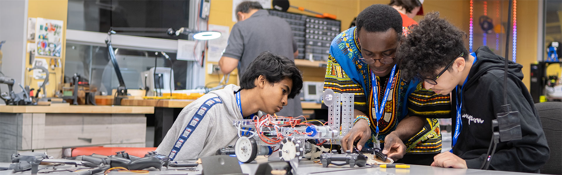 Two students and teacher working on robotics project in lab
