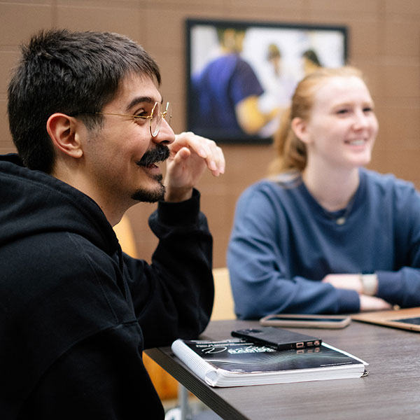 Male and female students seated at table, smiling
