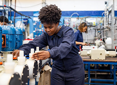 Woman in blue coveralls working in light manufacturing facility