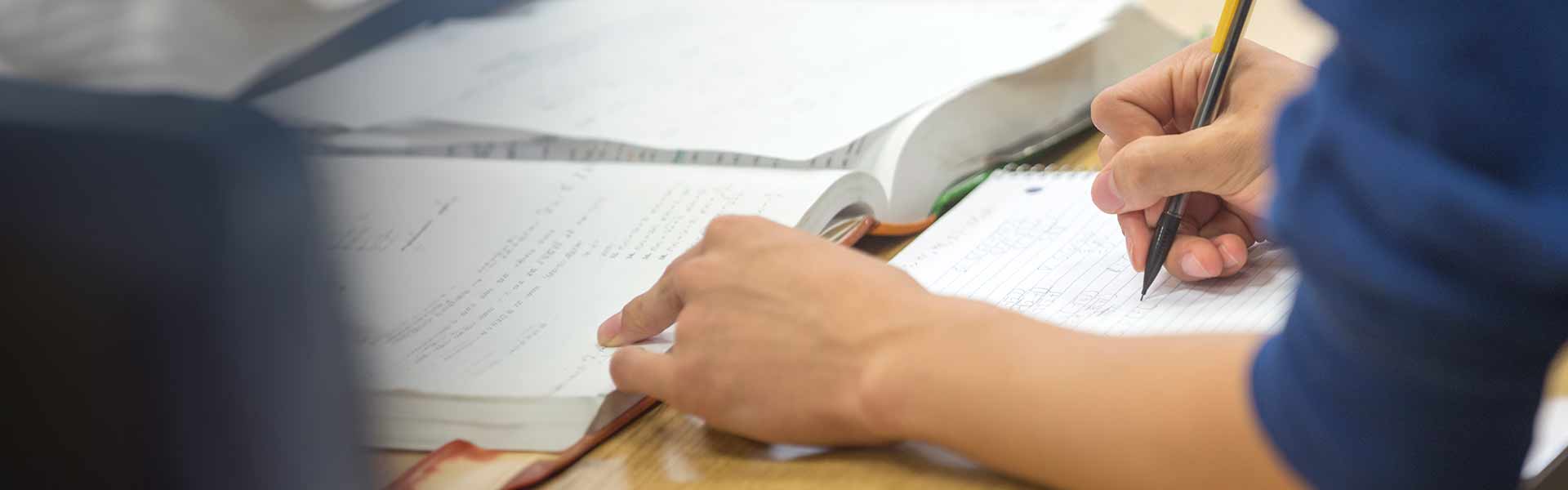 Close up of a students hands writing in a notebook with a mechanical pencil