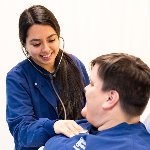 Nursing student listening to another student's heartbeat