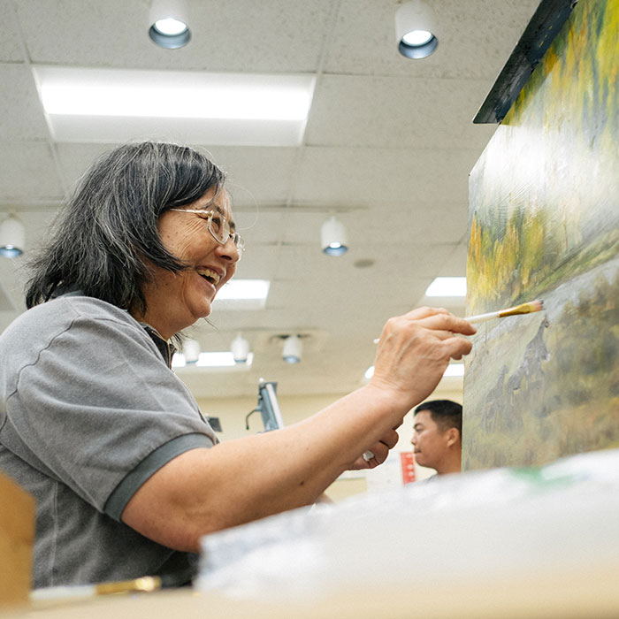 Woman painting while seated before an easel