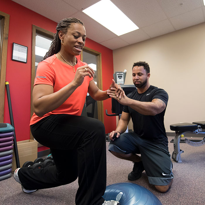 Female client doing exercises under the guidance of a trainer.