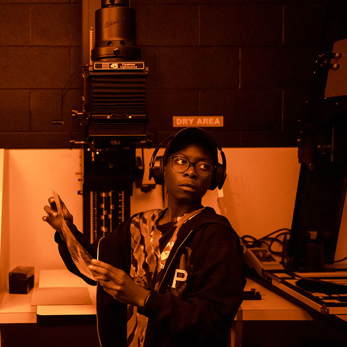 Student working under a red light in the photography studio