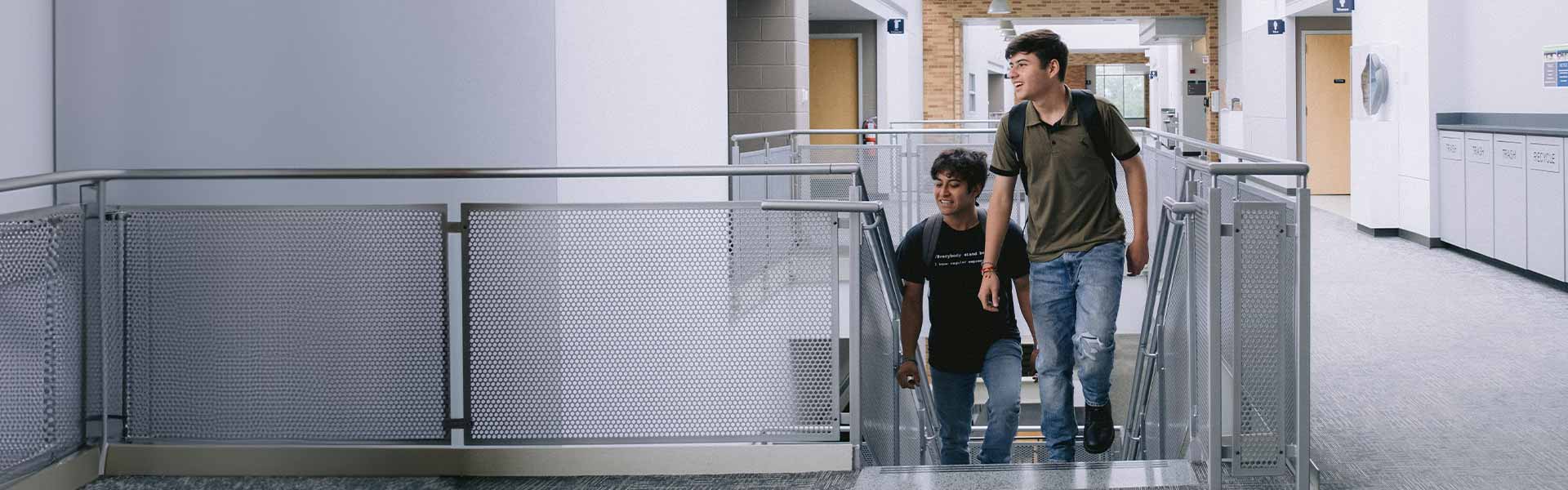 Two smiling students walking up stairs