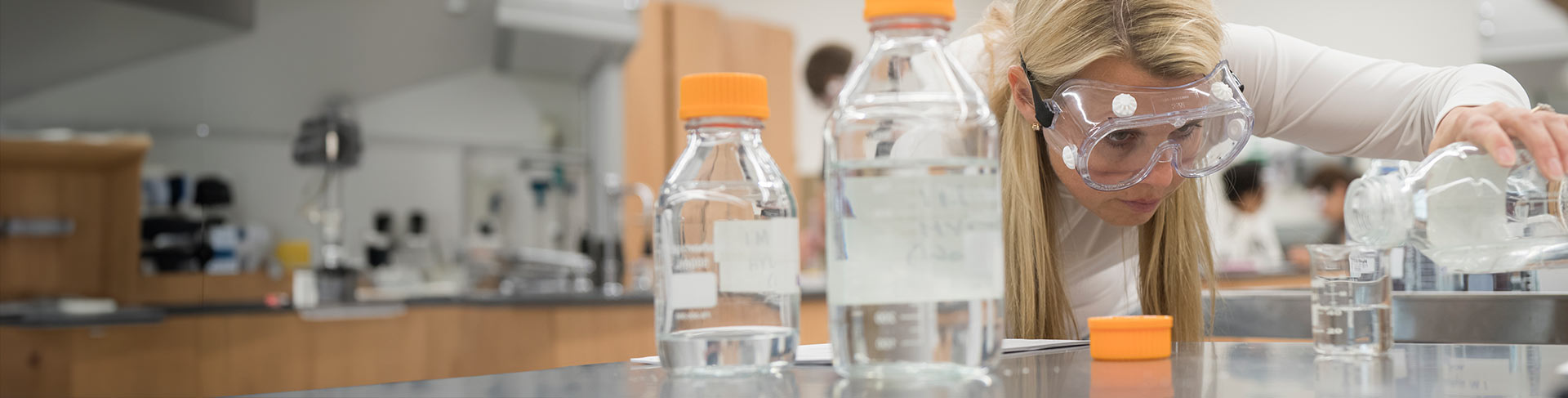 Student looking intently at pouring liquid in chemistry class