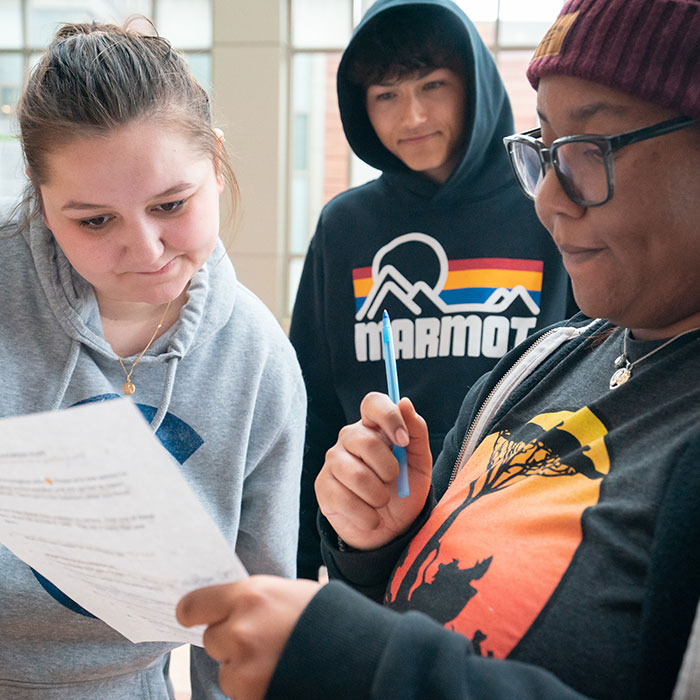 Three students looking at a sheet of paper with directions