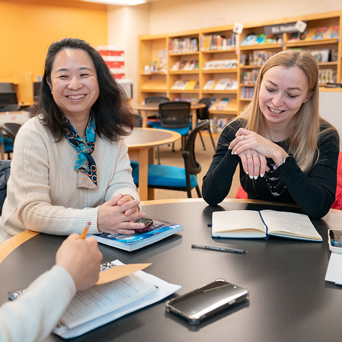 Students sitting at table in library, enjoying each other's company