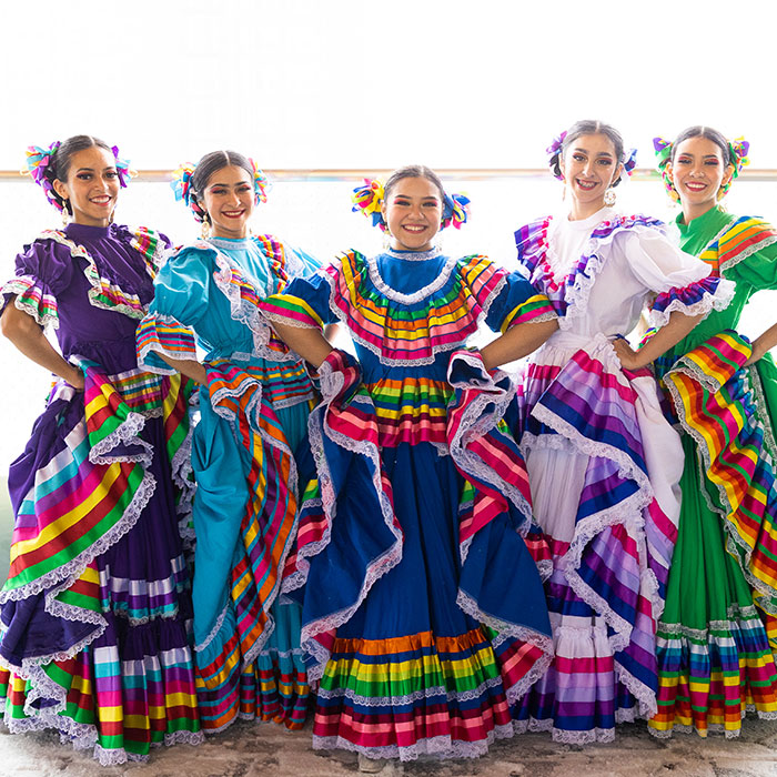 Five dancers in colorful dresses pose during a special event held at the Eleanor Murkey Community Center