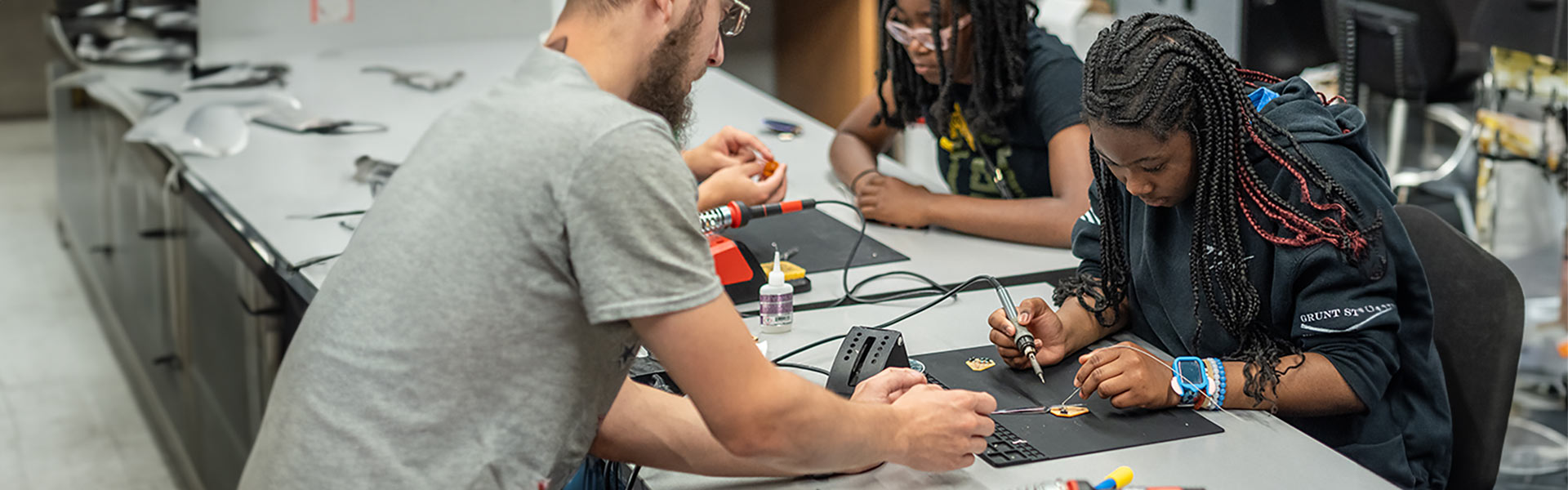 Young students work solder parts to make an electronic circuit.