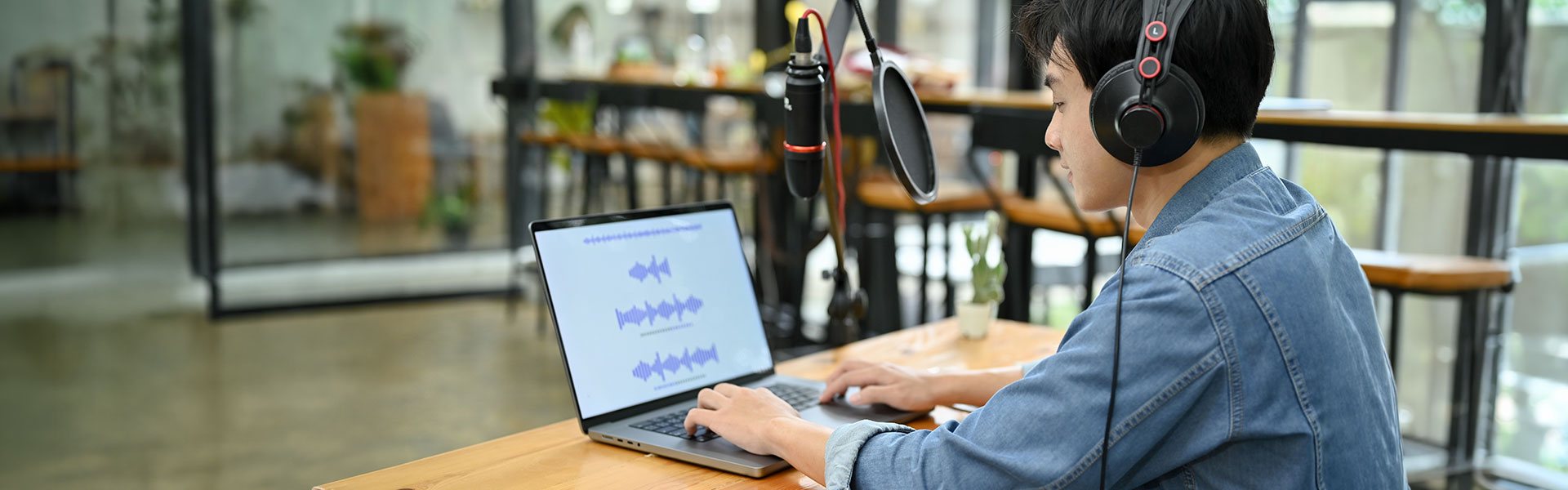 Student with laptop recording audio wearing headphones, speaking into microphone