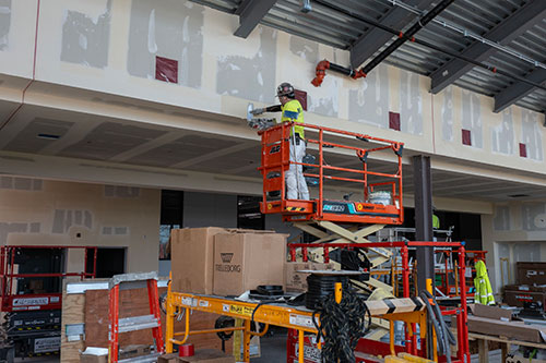 Worker on scissor lift doing drywall work inside new Urban Farm Center