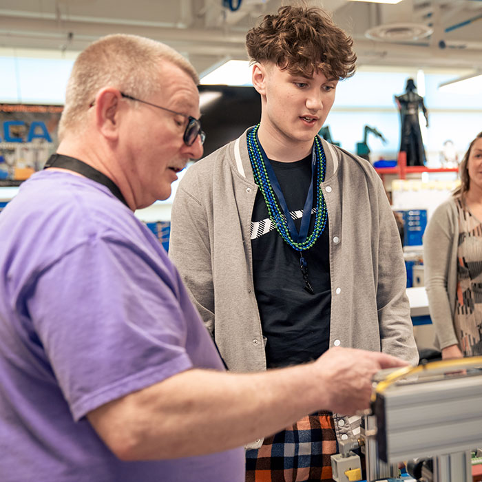 A volunteer explains equipment to a future student.